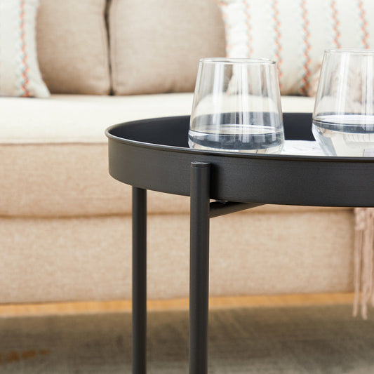 Black side table with two glasses on a blurred sofa background