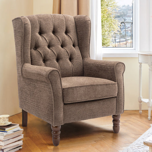 Brown upholstered armchair in a room with a window and books on a table.
