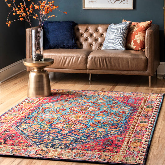 Living room with a brown leather sofa, colorful rug, and decorative pillows.
