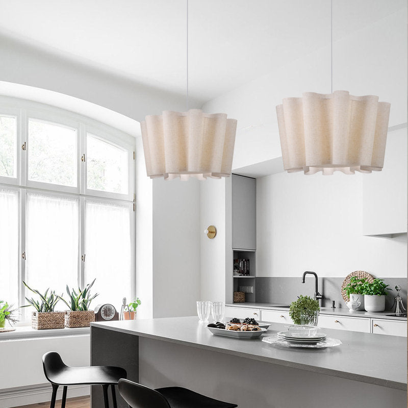 Dining room with wooden table, chairs, and a bench under two large fluted lamps.