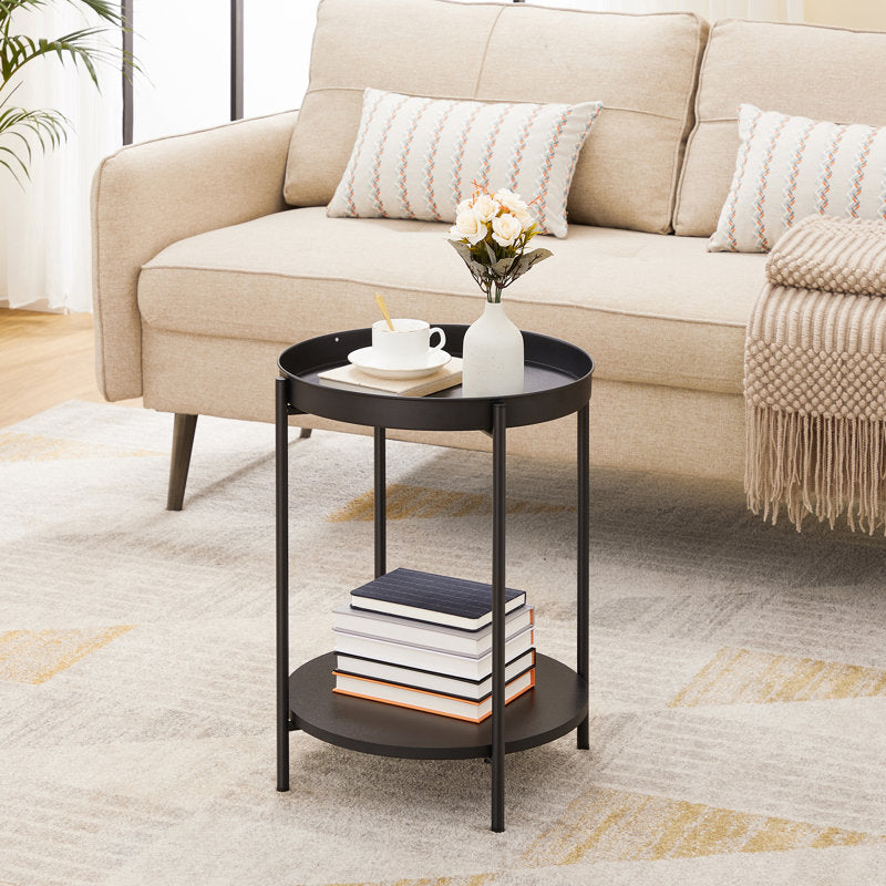 Black side table with books and a vase in front of a beige sofa.