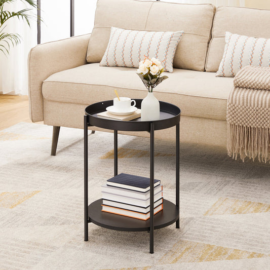 Black side table with books and a vase in front of a beige sofa.