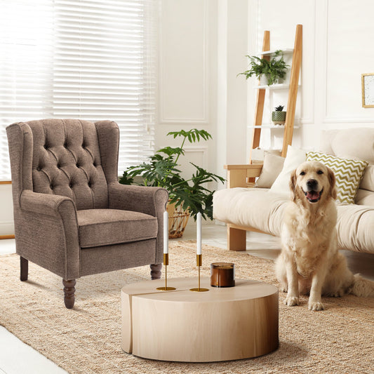 Dog sitting on a couch in a living room with a brown armchair and wooden coffee table.