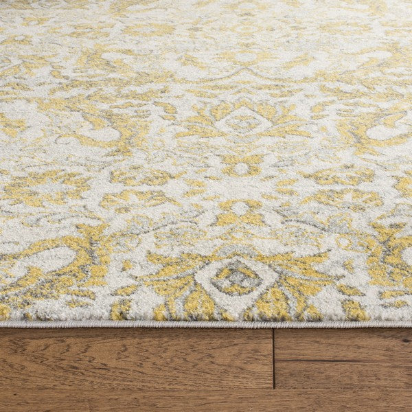 Close-up of a patterned rug with yellow and gray design on wooden floor.