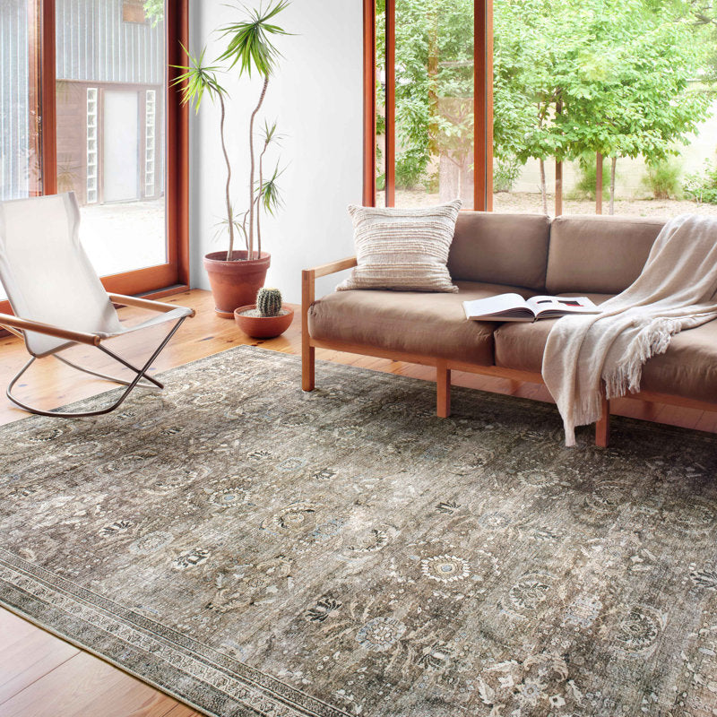 Living room with a patterned rug, sofa, chair, and plants.