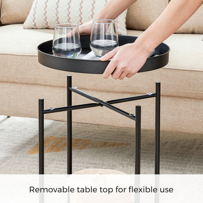 Black metal side table with a removable top, holding two glasses, in a living room setting.